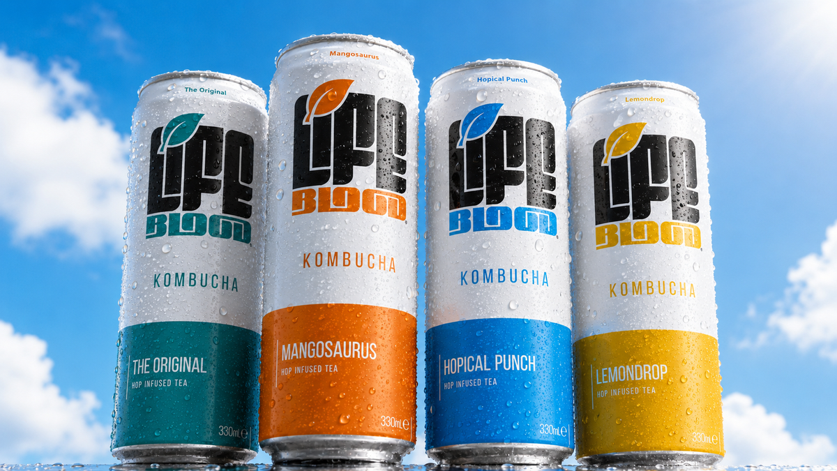 Four Life Blood Kombucha cans, The Original, Mangosaurus, Hopical Punch, and Lemondrop, chilled with condensation against a bright blue sky