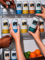 Hands reaching for chilled Life Blood kombucha cans in a fridge